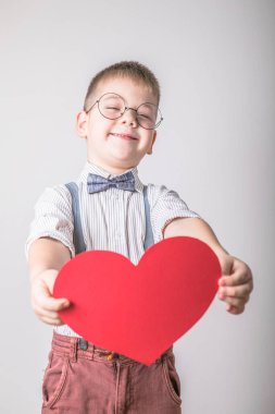 Beş yaşındaki gülümseyen çocuk aşkın, ailenin ve umudun kırmızı kalp sembolünü taşıyor. Sevgililer Günü 'nde kart geçmişi ya da aile ve çocukların korunmasıyla ilgili sosyal afişler.