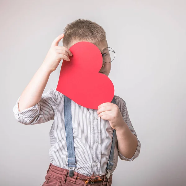 Beş yaşındaki gülümseyen çocuk aşkın, ailenin ve umudun kırmızı kalp sembolünü taşıyor. Sevgililer Günü 'nde kart geçmişi ya da aile ve çocukların korunmasıyla ilgili sosyal afişler.