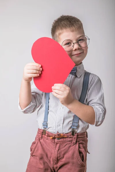 Five year old smiling boy holding a red heart  symbol of love, family, hope. Backgrounds for cards on Valentine\'s Day or social posters about the preservation of the family and children.