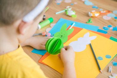 Paskalya tebrik kartı için küçük çocuk Bunny 'i tutuyor. Çocuk sanat projesi. DIY kavramı