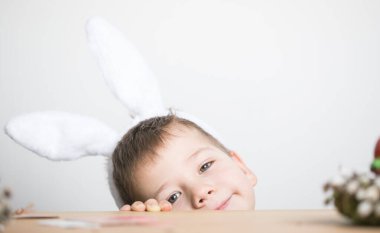 Paskalya yumurtası avında eğleniyoruz. Paskalya günü tavşan kulağı takan çocuk.