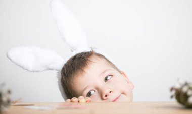 Paskalya yumurtası avında eğleniyoruz. Paskalya günü tavşan kulağı takan çocuk.