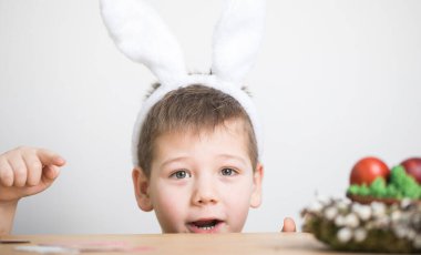 Paskalya yumurtası avında eğleniyoruz. Paskalya günü tavşan kulağı takan çocuk.