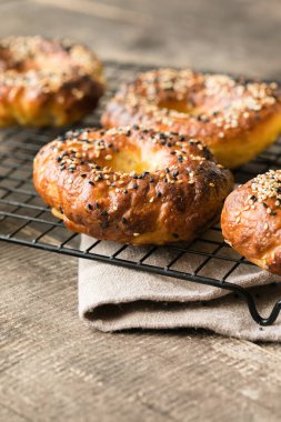 Gri ahşap arka planda susamlı simit, taze pişmiş Amerikan simidi.
