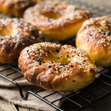 Gri ahşap arka planda susamlı simit, taze pişmiş Amerikan simidi.