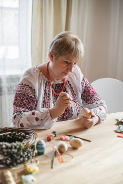 Ukrayna gömlekli emekli kadın paskalya yumurtası boyadı. DIY paskalya yumurtası yapıyor.