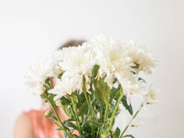 Meçhul kavram. Krisantemas buketi olan güzel genç bir kadın. Bahar portresi. Parlak beyaz çiçekler kızın ellerinde.