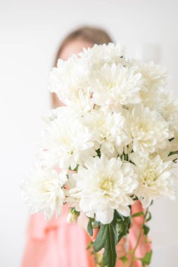 Meçhul kavram. Krisantemas buketi olan güzel genç bir kadın. Bahar portresi. Parlak beyaz çiçekler kızın ellerinde.