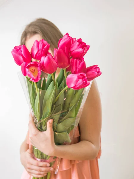 Faceless concept. Beautiful young woman with tulip bouquet. Spring portrait. Bright pink flowers in girl\'s hands.