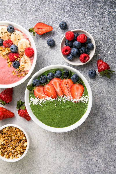 Matcha green tea breakfast superfoods smoothies bowl topped with strawberries, blueberries, coconut flakes Overhead, top view, flat lay