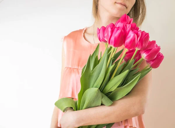 Beautiful young woman with tulip bouquet. Spring portrait. Bright pink flowers in girl's hands.