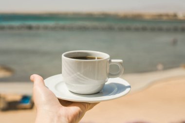 Kadın eli bir fincan kahve tutuyor. Günaydın gündoğumu konsepti. Yeni bir güne başlayalım. Metin için boşluk