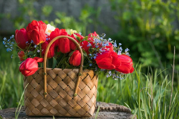 Summer  flowers in straw basket. Provence flowers with wildflowers, red tulips, field, village, Provence