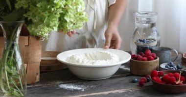 Kadın adım adım pierogi tarifi yapmak için spatulayla hamura şeker, tuz ve yumurta ekler.