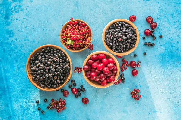 Fresh organic summer berries mix on blue concrete  background. Blueberries, red black currant and cherries. Top view. Concept of summer food. Flat lay, copy space