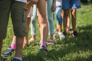 Takım oyunundaki çocuklar. Çocuklar dışarıda birlikte hareket ediyor ve bir çocuğun bacakları önünde hareket ediyor.