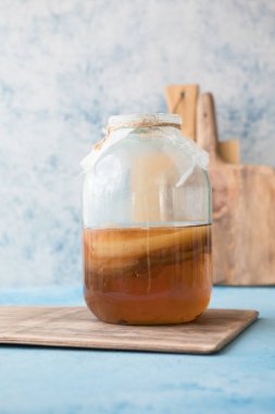 Çiğ mayalanmış ev yapımı alkolik ya da alkolsüz kombu çayı. Buzlu çay ve sağlıklı doğal probiyotik. Mavi arka planda naneli.