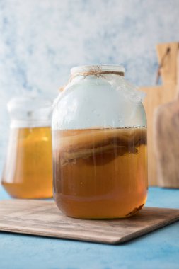 Çiğ mayalanmış ev yapımı alkolik ya da alkolsüz kombu çayı. Buzlu çay ve sağlıklı doğal probiyotik. Mavi arka planda naneli.