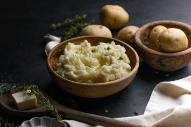 Köy arka planında çiğ patates ve baharatlı kremalı patates püresi.