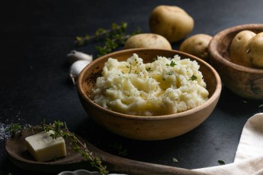 Köy arka planında çiğ patates ve baharatlı kremalı patates püresi.