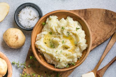 Köy arka planında çiğ patates ve baharatlı kremalı patates püresi.