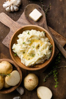 Köy arka planında çiğ patates ve baharatlı kremalı patates püresi.