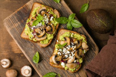 Mantarlı sağlıklı avokado tostu ve tam tahıllı ekmeğin üzerinde taze otlar.
