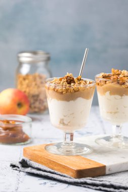 Karamel soslu lezzetli elmalı parfe ve cam tatlı bardaklarında servis edilen gevrek fındıklar.