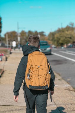 Sırt çantalı 10 yaşında bir çocuk Amerikan okulundan eve yürüyor, doğal gündüz fotoğrafı..