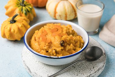 Kayısı ve kuru üzümlü ev yapımı balkabağı lapası mavi arka planda sıcak sonbahar kahvaltısı.