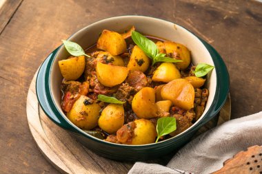 Samimi ev yapımı patates güveci, yumuşak et ve rengarenk sebzeler kırsal ahşap bir masada servis edilir..