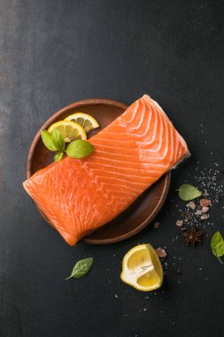 Somon balığı. Taze çiğ somon balığı filetosu ve taş zemin üzerinde pişirme malzemeleri, üst görünüm.
