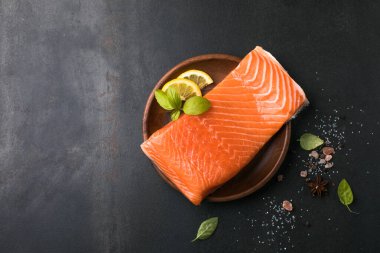 Somon balığı. Taze çiğ somon balığı filetosu ve taş zemin üzerinde pişirme malzemeleri, üst görünüm.