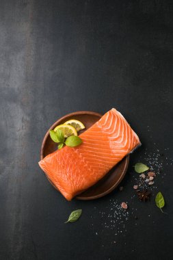 Somon balığı. Taze çiğ somon balığı filetosu ve taş zemin üzerinde pişirme malzemeleri, üst görünüm.