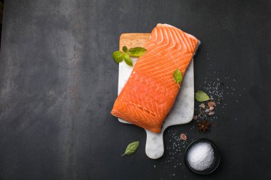 Somon balığı. Taze çiğ somon balığı filetosu ve taş zemin üzerinde pişirme malzemeleri, üst görünüm.