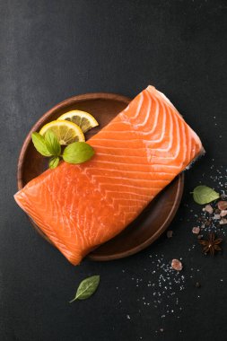 Somon balığı. Taze çiğ somon balığı filetosu ve taş zemin üzerinde pişirme malzemeleri, üst görünüm.