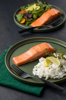 İki pişmiş somon fileto pirinçli ve yeşil arka planda.