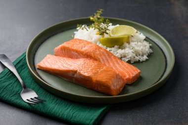 İki pişmiş somon fileto pirinçli ve yeşil arka planda.