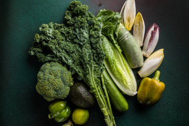 Koyu bir arka planda düz olarak dizilmiş çeşitli yeşil sebzeler. Sağlıklı yeşil gıda, organik sebzeler.