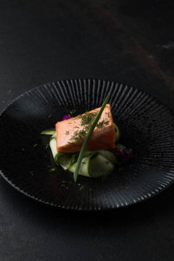 Saku usulü taze çiğ somon, siyah bir tabakta servis edilir. Minimalist Japon kaynaklı gıda sunumu.