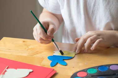 Çocuk Ukrayna bayrağı renginde tahta Paskalya tavşanı boyuyor