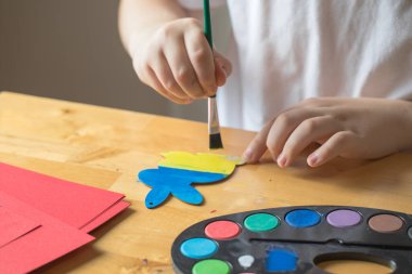 Çocuk Ukrayna bayrağı renginde tahta Paskalya tavşanı boyuyor