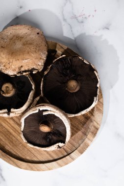 Köy ahşap kesme tahtasına dizilmiş büyük taze şampiyon mantarları. Hammadde ve organik pişirme kavramını vurgulayan basit doğal kompozisyon.