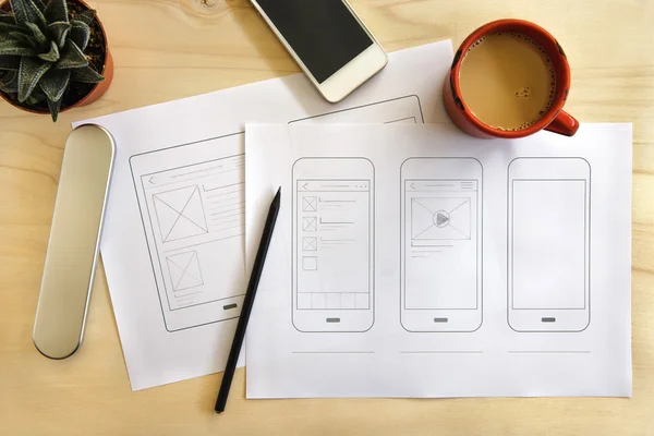 Дизайнерский стол с мобильным приложением wireframe — стоковое фото