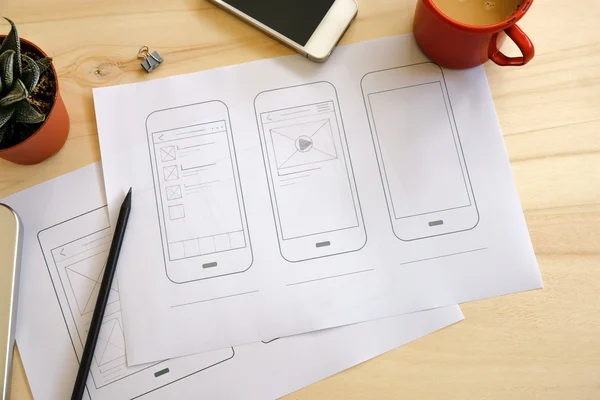 Mesa de designer com esboços de wireframe UI — Fotografia de Stock