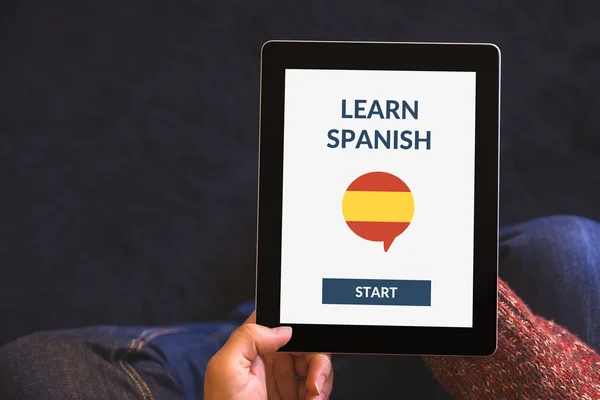 Manos sosteniendo la tableta con en línea aprender concepto español en la pantalla — Foto de Stock