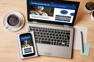 Coronavirus en son haber konsepti dizüstü bilgisayar ve ahşap masanın üzerinde akıllı telefon ekranı. Üst görünüm