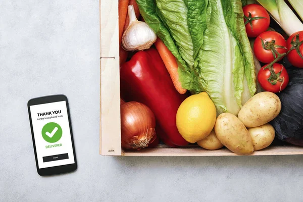 新鲜食品递送服务的概念 在家里可以看到一个装有新鲜蔬菜的智能手机和木箱 网上购物订单 — 图库照片