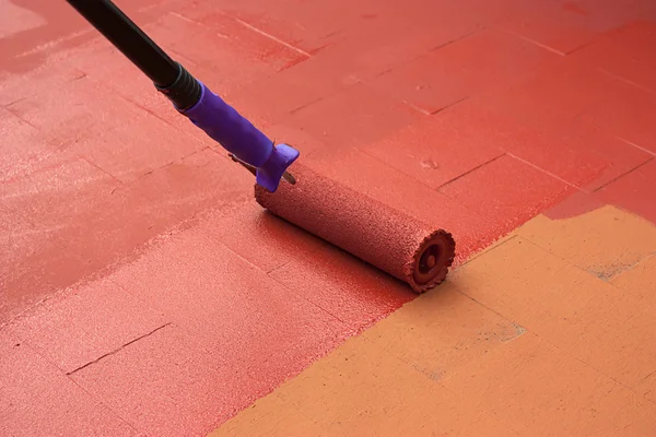 Kontraktmaler streicht einen Fußboden auf Farbe Rot — Stockfoto