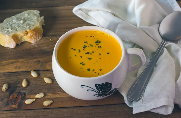 Pumpkin soup in white bowl on wooden table — Stock Photo, Image